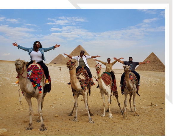 A group of people riding on the backs of camel.